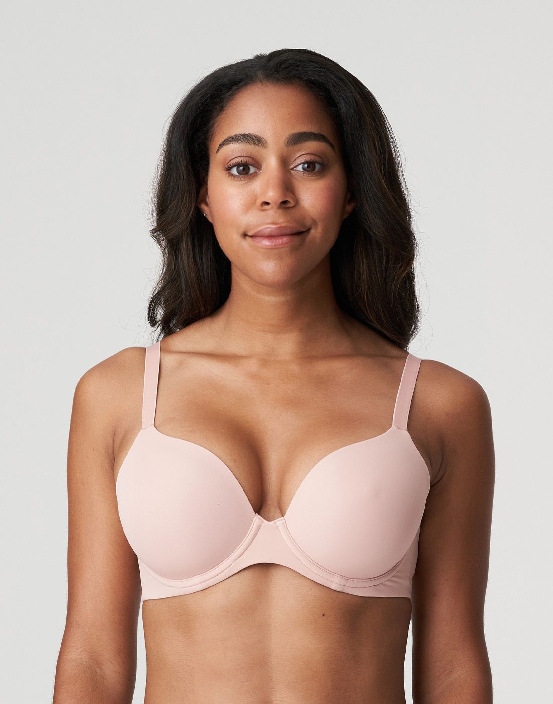 mørk kvinne med pudderosa t-skjorte BH