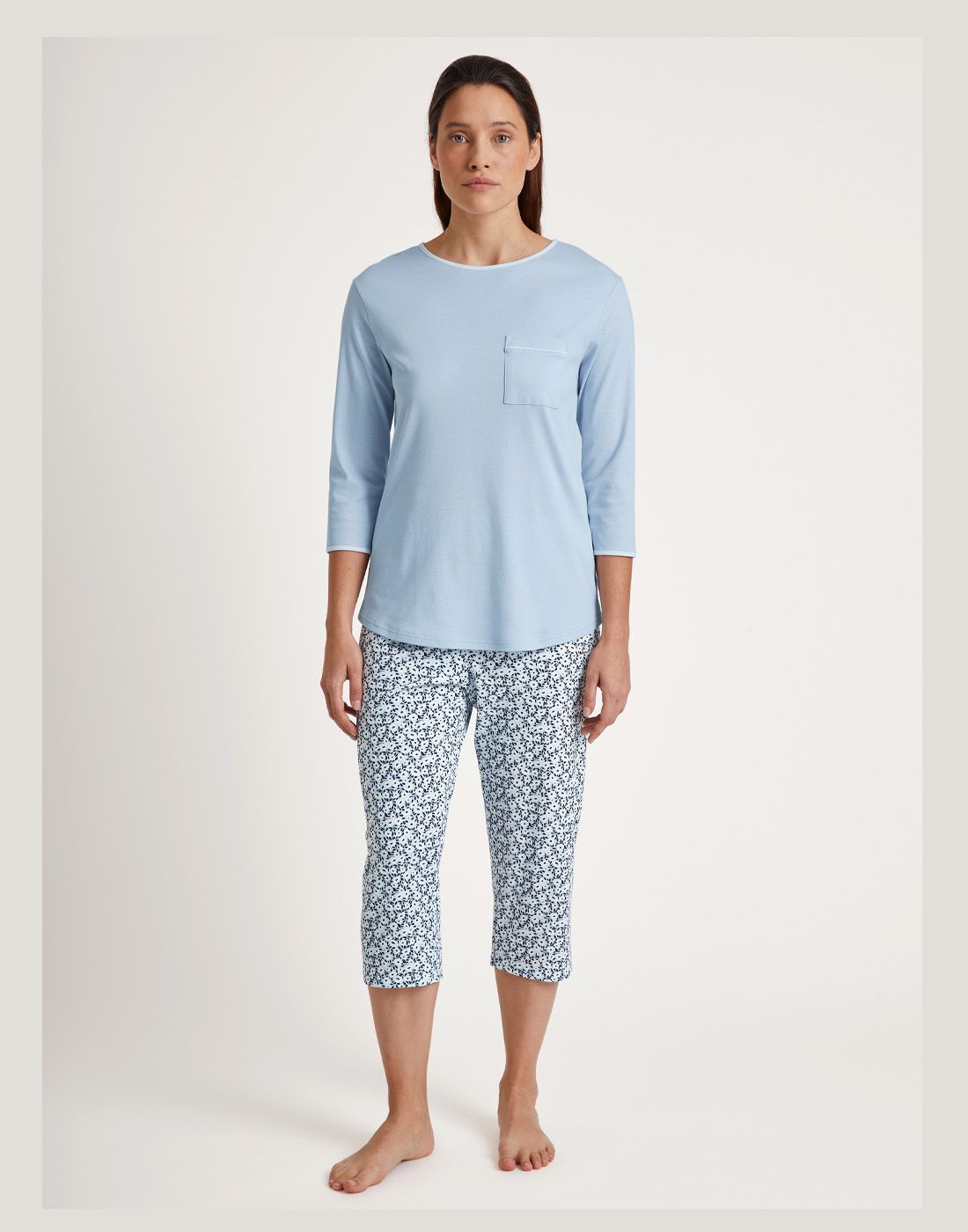 kvinne med pysj i bomull med blå genser og mønstret bukse