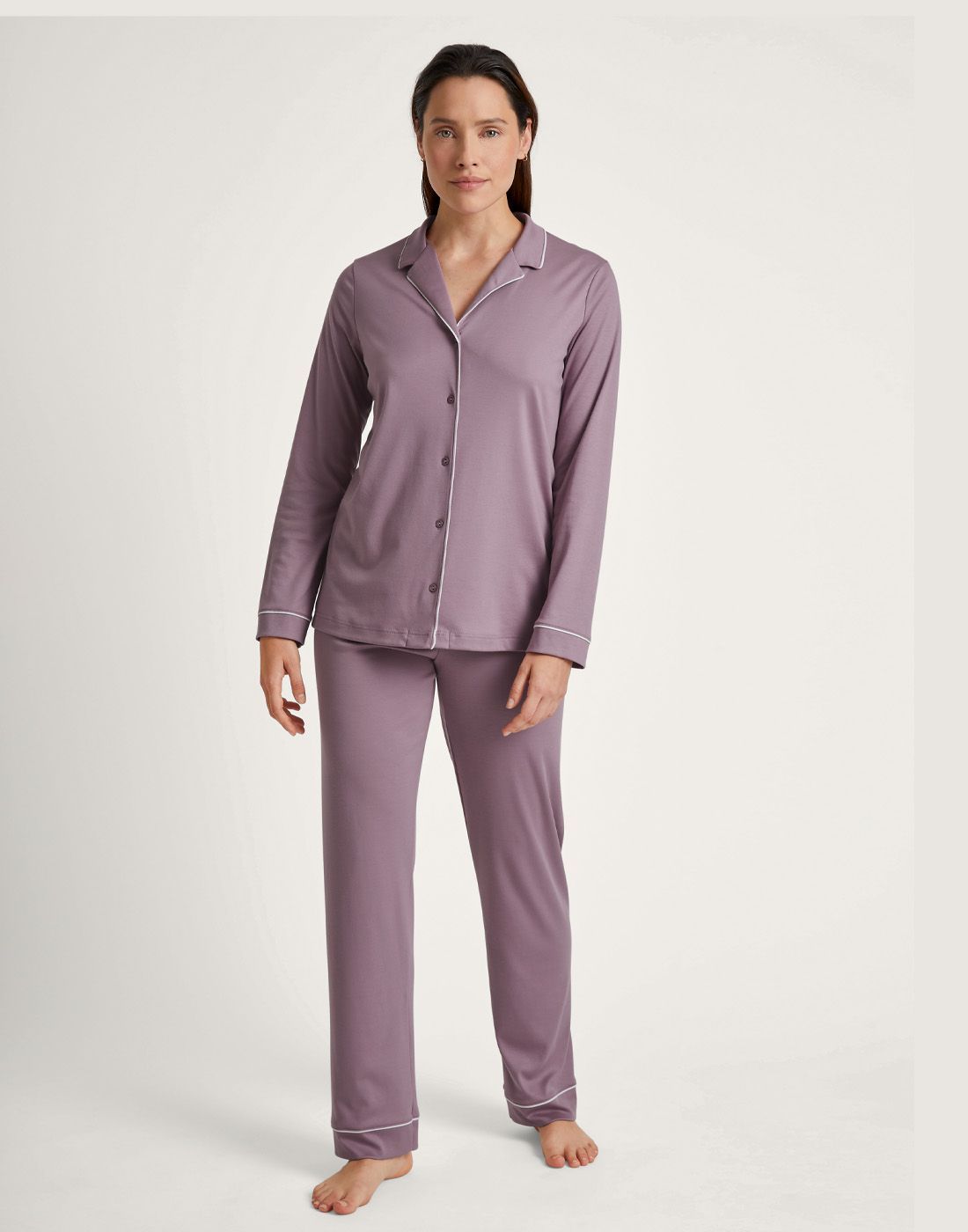 mørk kvinne i rosa pysj med skjorte og bukse